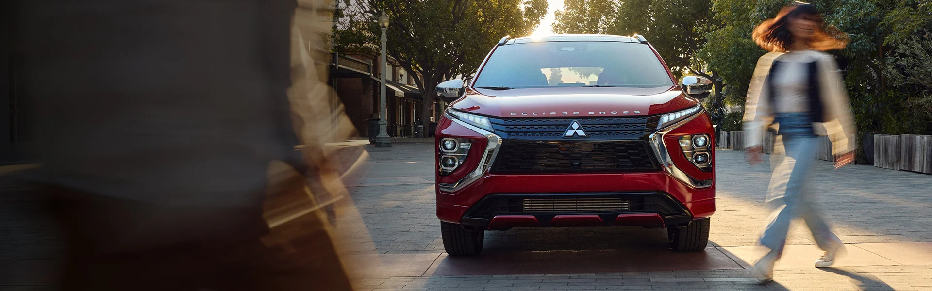 Front view of a new Mitsubishi vehicle with a woman crossing the street