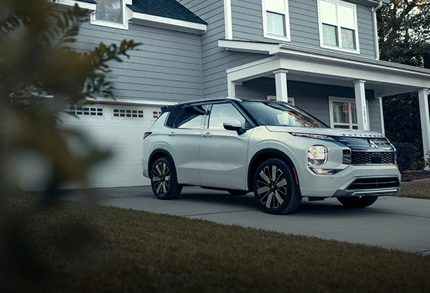 A white Mitsubishi vehicle parked infront of a home