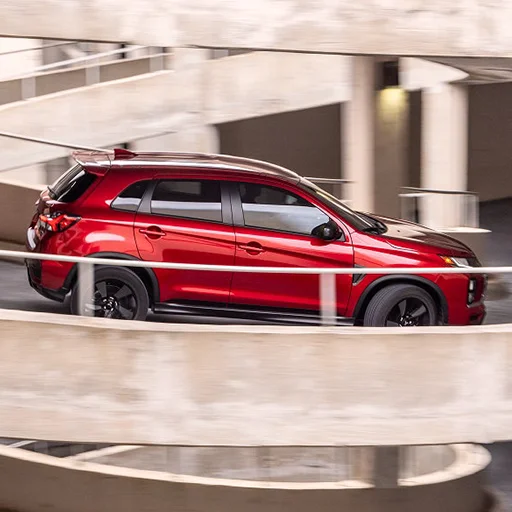 Action shot of a red Mitsubishi driving down a spiral road from a car parking garage