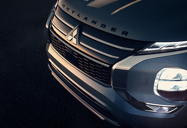 Grill of a Silver Outlander with the Mitsubishi Logo in Focus