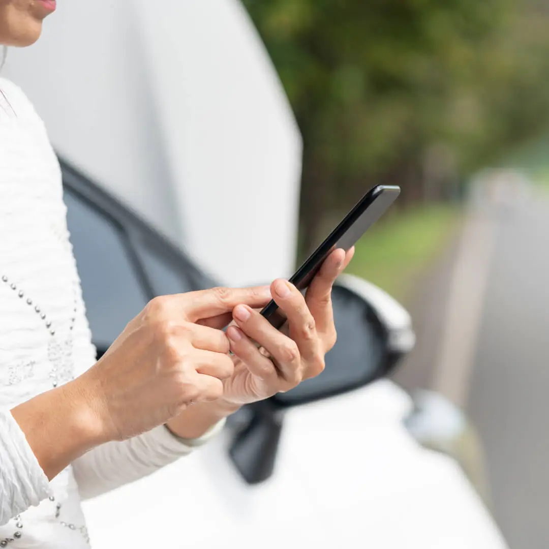 Woman using her phone to use Mitsubishi's Roadside Assistance services