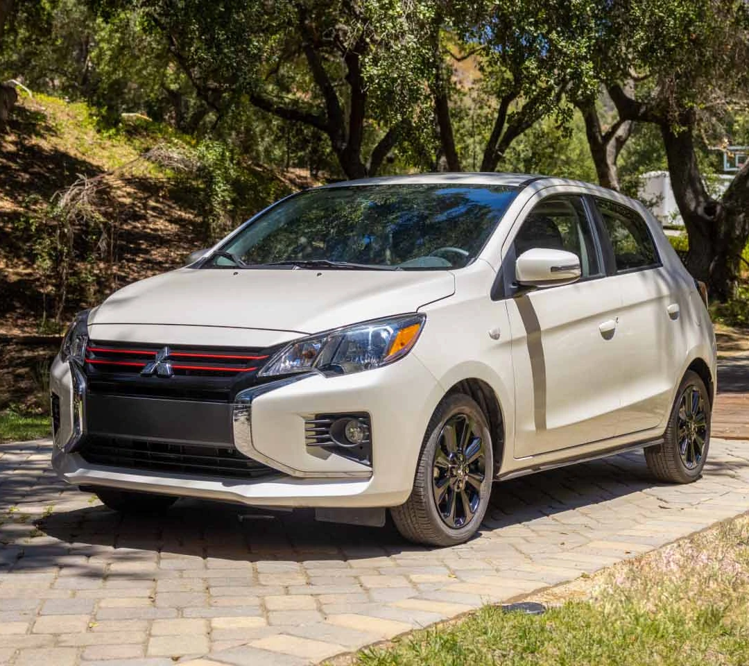 A white 2023 Mitsubishi Mirage hatchback waiting for Roadside Assistance service in a driveway