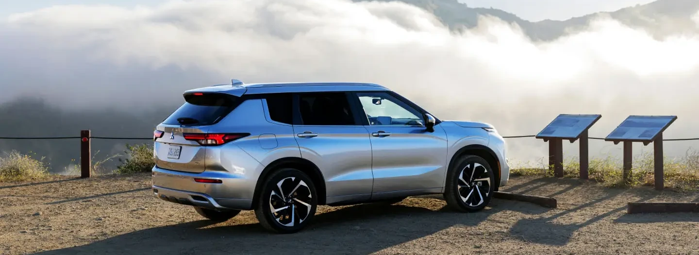 Front view of a new Mitsubishi vehicle with a woman crossing the street